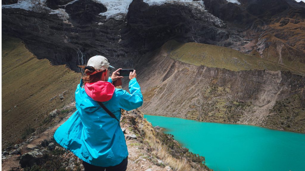 Tourist taking a photo of the turquoise Humantay Lake, demonstrating a tip from the Humantay Lake Guide altitude tips.