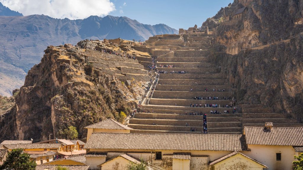 Aerial view of an Inca fortress surrounded by mountains and agricultural terraces.