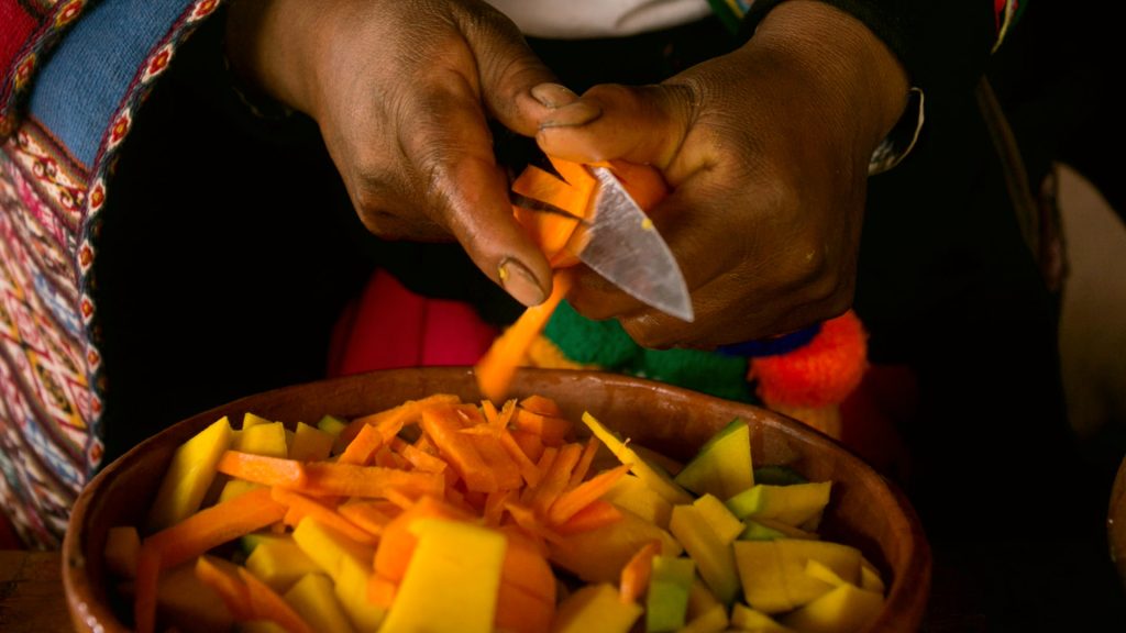 Close-up of hands dicing brightly colored vegetables, representing ancient Inca Culture food preparation - Ali Peru Treks.