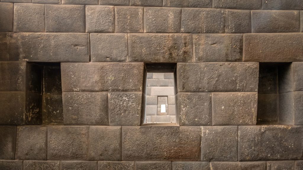 Close-up of the finely crafted Inca stone walls at Qorikancha, Cusco, showcasing the incredible precision and architectural skills of the ancient civilization. - Ali Peru Trek.