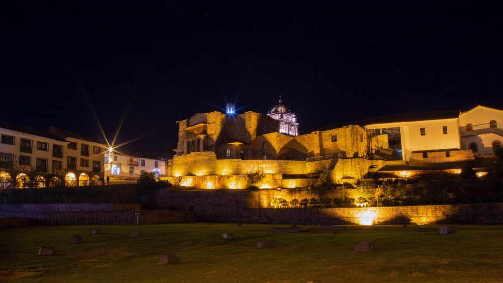 Illuminated night view of Qorikancha in Cusco, Peru, showcasing the majestic Inca and colonial architecture under a starry sky. - Ali Peru Trek.
