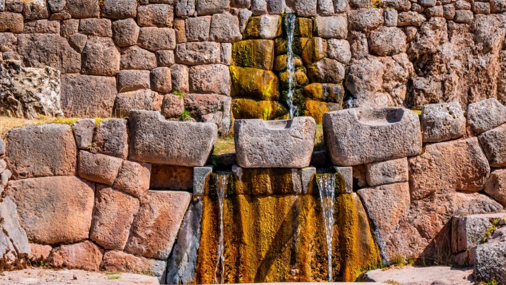 Incan water fountains in Tambomachay, featuring impressive stone architecture and a continuous flow of water. - Ali Peru Treks