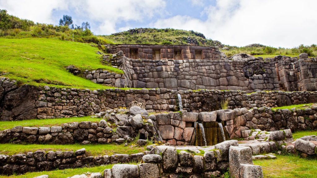 Panoramic view of the Tambomachay archaeological complex in Cusco, featuring Incan terraces and sacred water fountains. - Ali Peru Treks