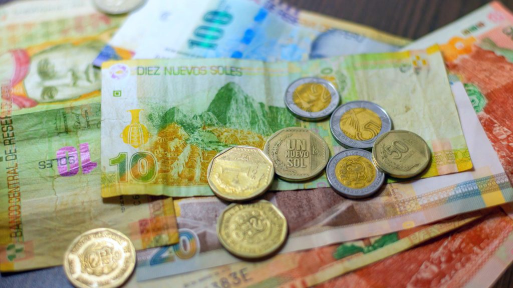 Assorted Peruvian currency including colorful banknotes and coins, useful for planning the Lares Trek Packing List – Ali Peru Treks