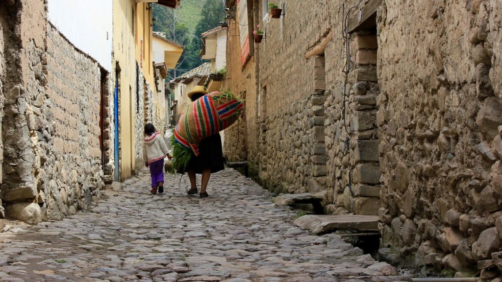 Local woman and child walking on a cobbled street in Ollantaytambo town - Ali Peru Treks