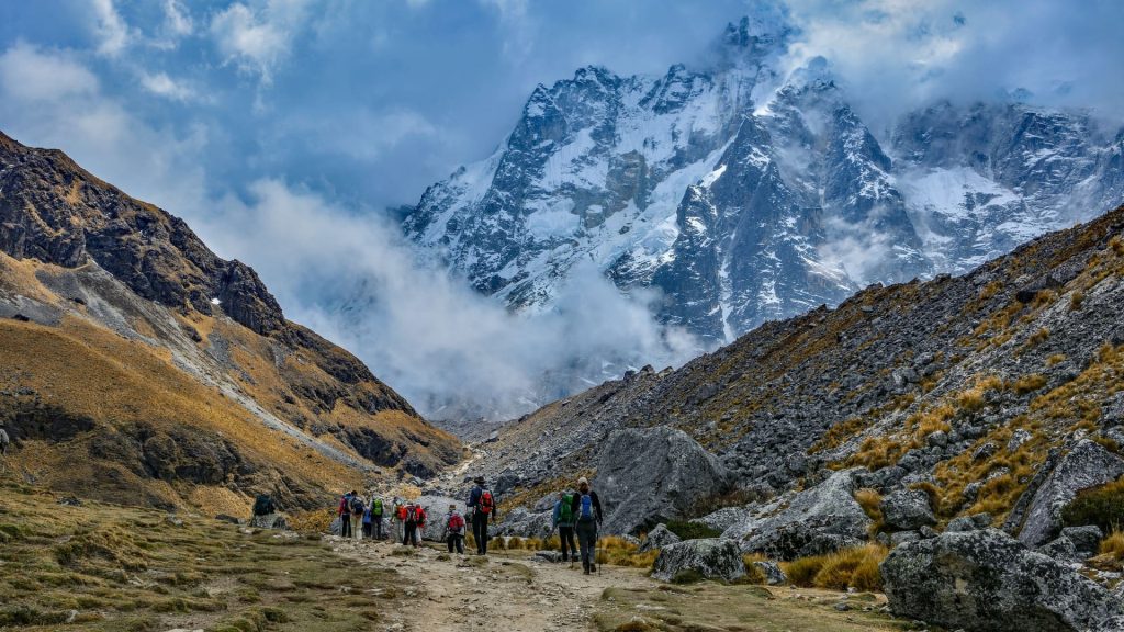 Group of hikers on the Salkantay trail in the Peruvian Andes with snow-capped peaks, comparing Lares Trek vs Salkantay Trek routes - Ali Peru Treks