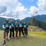 A group of people posing with hiking poles in front of the ruins of Machu Picchu in Peru