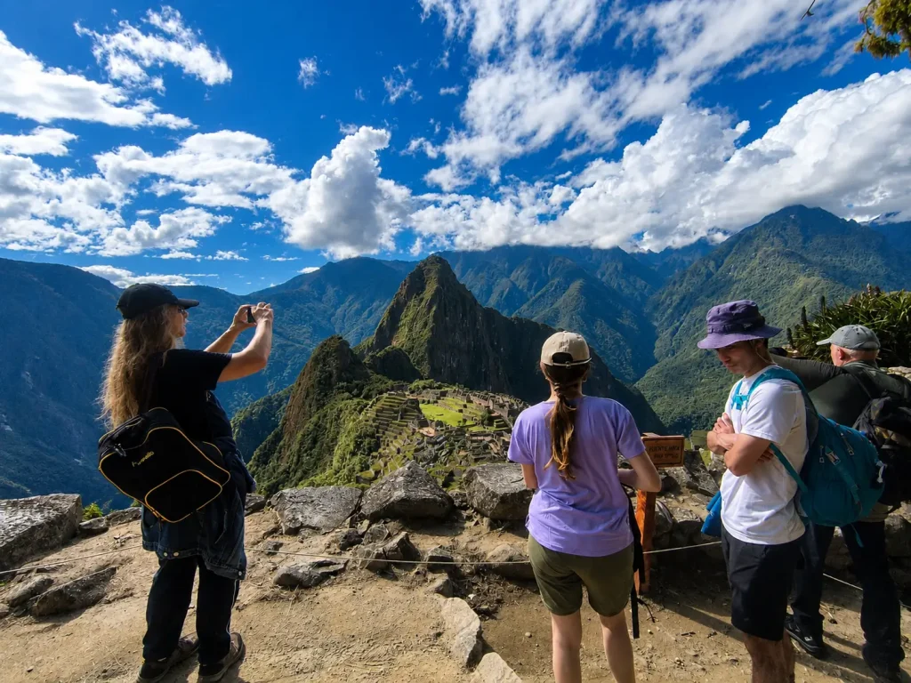 A group of tourists enjoying a breathtaking panoramic view of the Inca citadel of Machu Picchu