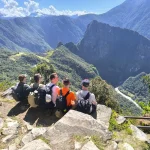 A group of tourists enjoying a panoramic view of the Machu Picchu archaeological complex from the famous Sun Gate, or Inti Punku