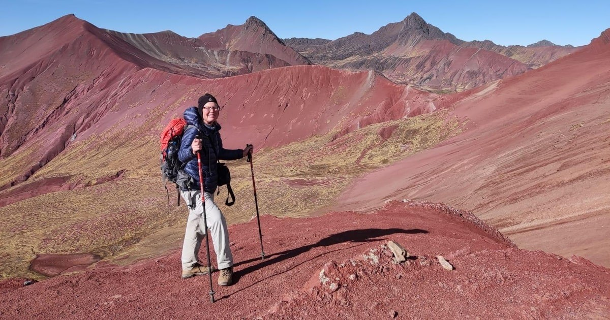Hiker standing on the vibrant slopes of the Red Valley near Rainbow Mountain