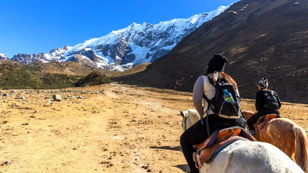 Hikers on the trail to Humantay Lake surrounded by green valleys and towering snow capped peaks in the Peruvian Andes