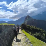 The Inca Trail to Machu Picchu, specifically in the upper section near the citadel, with hikers walking along the historic trail